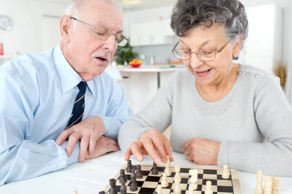 Homme et femme âgés jouant aux échecs à la maison — Photo