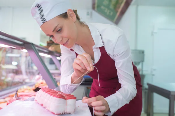 Positieve vrouwelijke slager voorbereiden product — Stockfoto