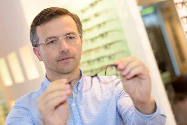 Mann im Optiker schaut auf Rahmen — Stockfoto