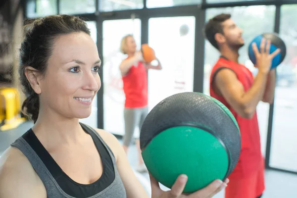 Stark frisk kvinna håller tunga medicin boll i gym träning — Stockfoto