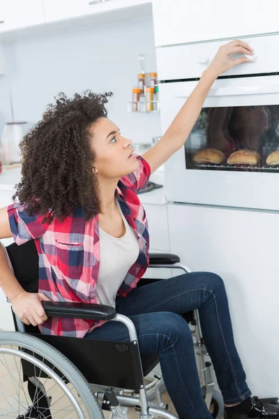 Disabled woman in wheelchair preparing meal in kitchen — Stock Photo, Image