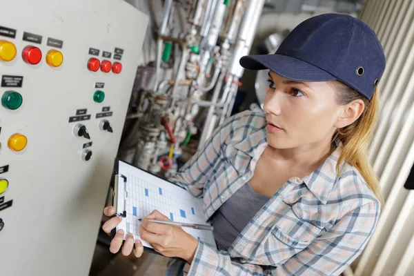 Kvinna svarvning knapparna på maskinen i fabriken — Stockfoto