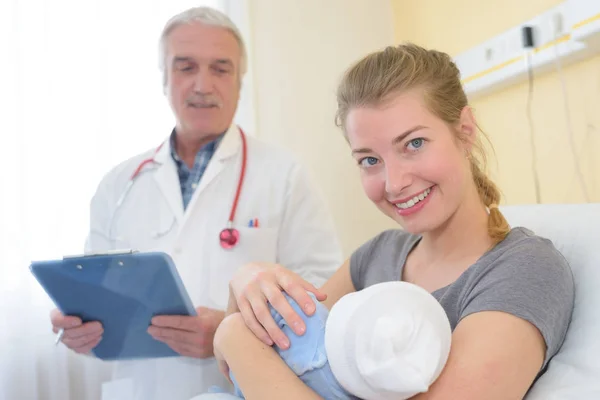 Ärztin und lächelnde Frau mit Baby — Stockfoto