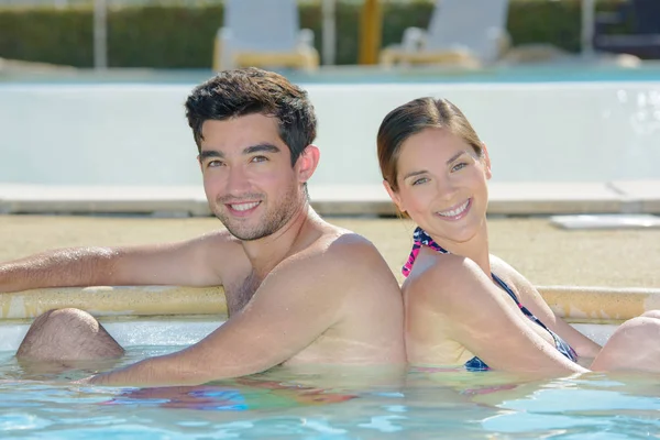 Paar sitzt Rücken an Rücken im Schwimmbad — Stockfoto