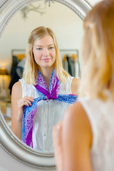거울 앞에서 스카프를 시도 하는 여자 — 스톡 사진