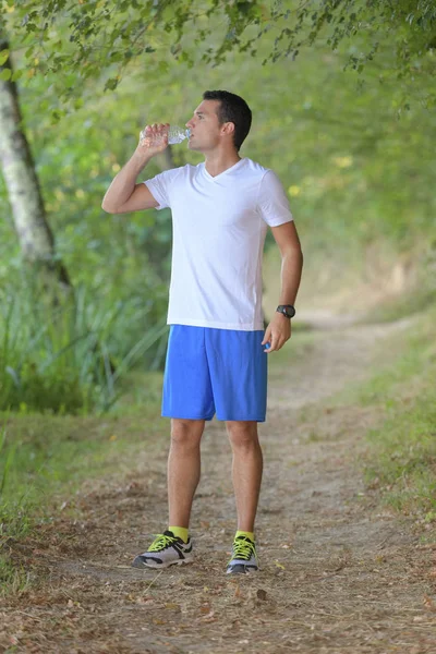 Actieve man drinkbaar water uit een fles buitenshuis — Stockfoto