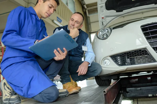 Mekaniker hjälper lärling att fixa motorn — Stockfoto