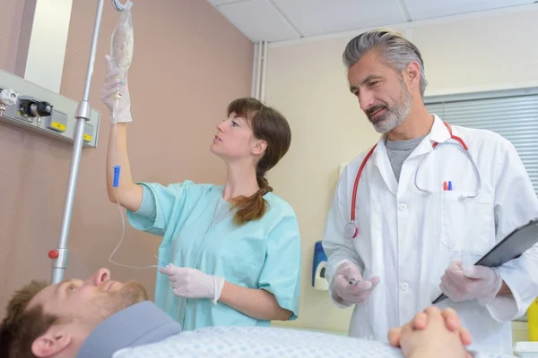 Enfermeira verificar os pacientes gotejamento enquanto médico falando — Fotografia de Stock