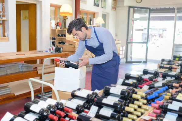Vendedor masculino en uniforme bodega botella vino en tienda de vinos — Foto de Stock