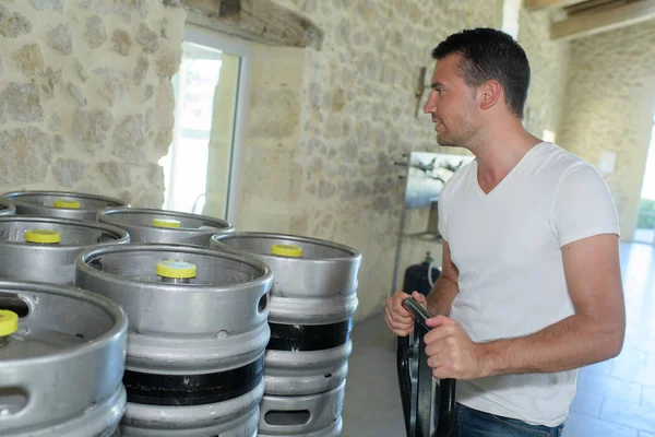 Porträt eines jungen Herstellers, der Fässer in Brauerei trägt — Stockfoto