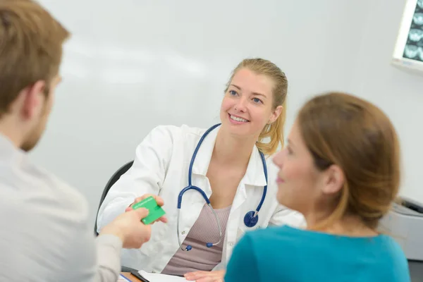 Une patiente remet sa carte à une jeune femme médecin — Photo