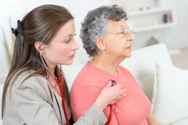 Medico donna visita donna anziana paziente a casa — Foto Stock