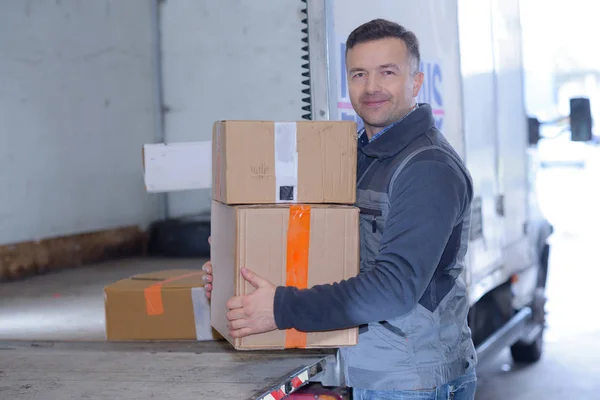 Trabajador de almacén moviendo cartones en su camión de reparto — Foto de Stock