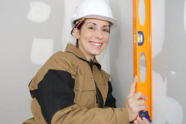 Pracownik kobieta nachylając poziomnicy na ścianie — Zdjęcie stockowe