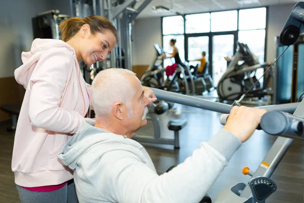 Homem sênior exercitando com treinador em estúdio de fitness — Fotografia de Stock