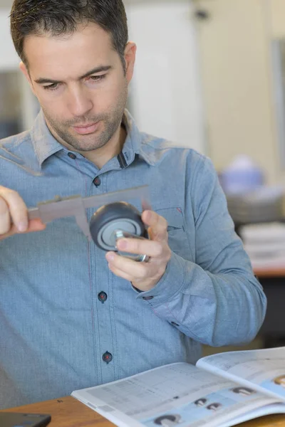 Hombre usando pinzas para medir rueda pequeña — Foto de Stock