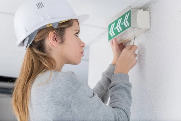 Tecnico donna che posiziona un segnale di uscita di emergenza — Foto Stock