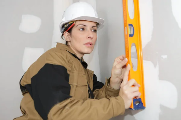 Mulher de pé e segurando um nível de espírito — Fotografia de Stock