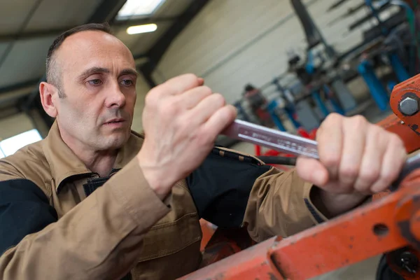 Technicus in fabriek op machine onderhoud met sleutel — Stockfoto