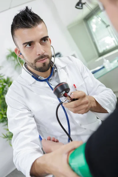 Junger Arzt nimmt Blutdruck des Patienten — Stockfoto