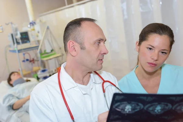 Mužský a ženský lékař při pohledu na pacienta xray — Stock fotografie
