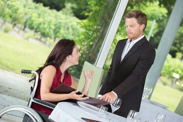 Vrouw in rolstoel roept de ober in het restaurant — Stockfoto