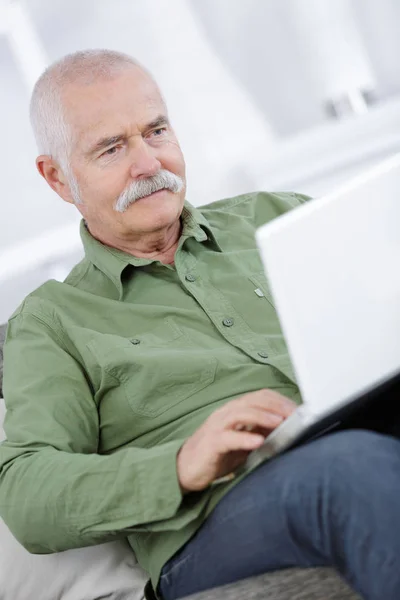 Heureux homme âgé utilisant un ordinateur portable à la maison — Photo