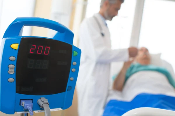 Elektronischer Herzmonitor, Patient und Arzt im Hintergrund — Stockfoto