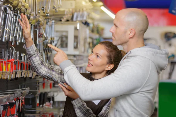 Manliga leverantör visar skiftnyckel till kvinnlig kund i hårdvara shop — Stockfoto