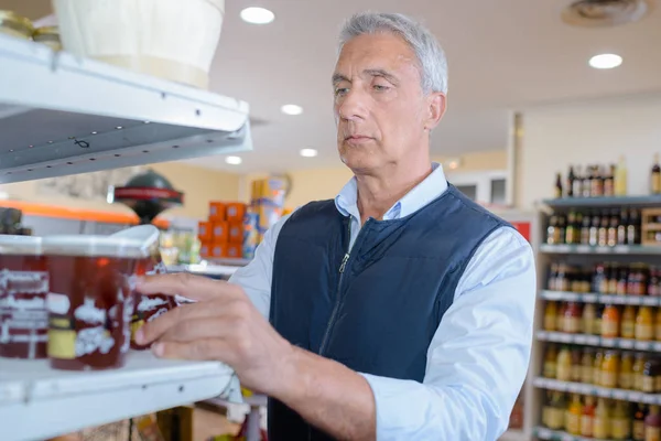 Homem escolhendo frasco de mel — Fotografia de Stock