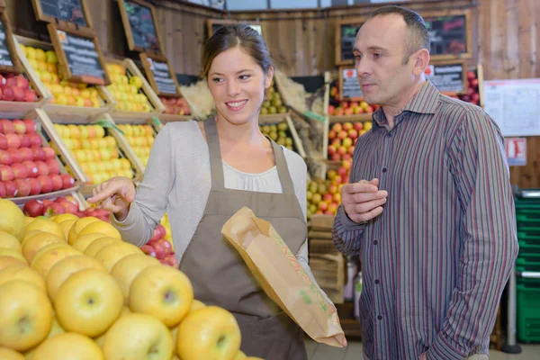 Shop assistant serving apples to customer — Stock Photo, Image