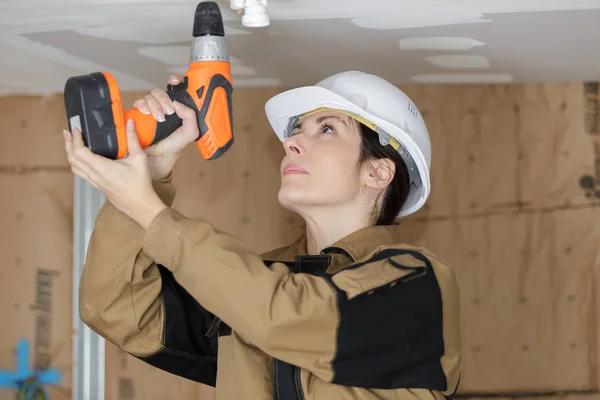 Mujer con perforador de construcción agujero de perforación en el techo —  Fotos de Stock
