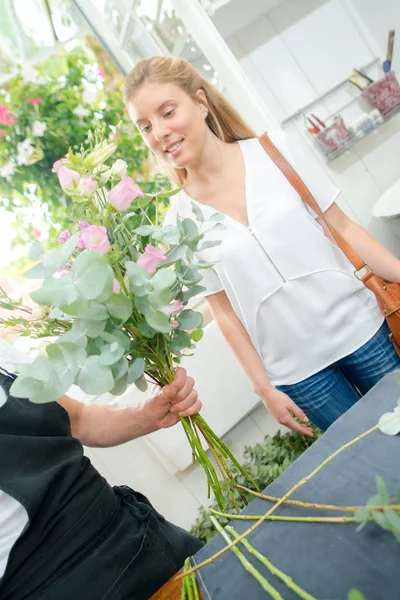 Флорист вручает заказчику высокий букет цветов — стоковое фото