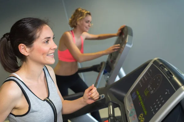 Duas mulheres desportivas correm na máquina no centro de fitness — Fotografia de Stock
