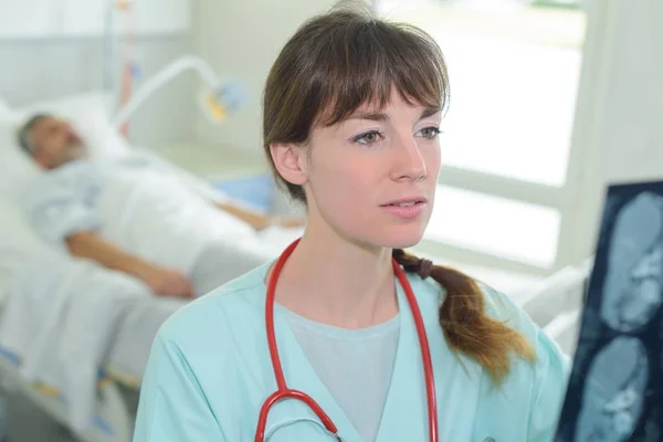 Junge Ärztin schaut sich Röntgenbild an — Stockfoto