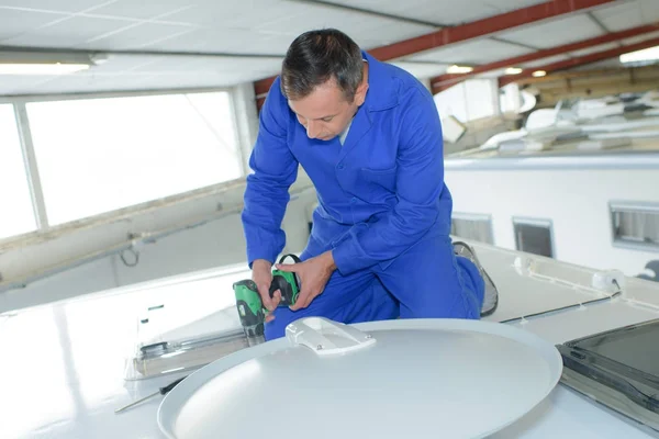 Mechanic using cordless drill on roof of camper van — Stock Photo, Image