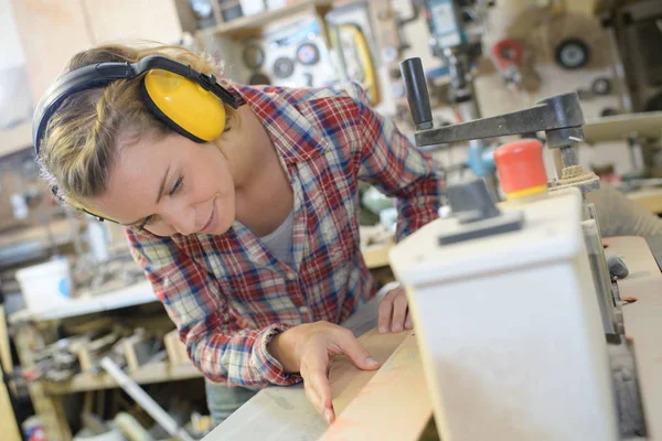 Genç kadın marangoz kesim ahşap atölyesinde tablesaw ile konsantre — Stok fotoğraf