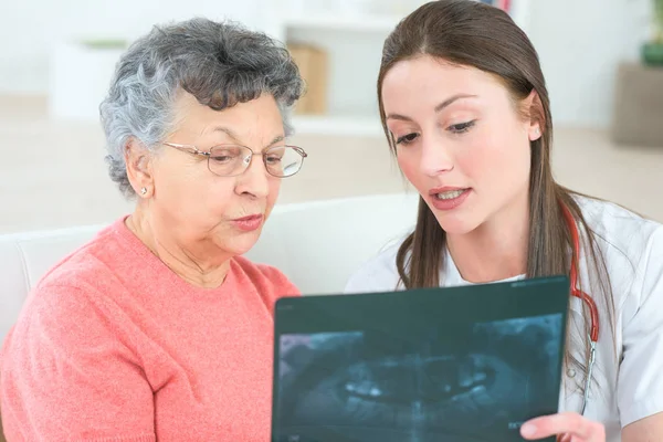 Доктор показывает рентген пожилому пациенту в больнице — стоковое фото