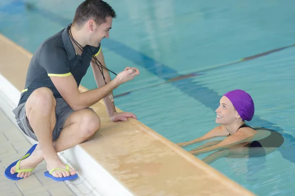 Fit trainer praten met zwemmer in leisure center — Stockfoto