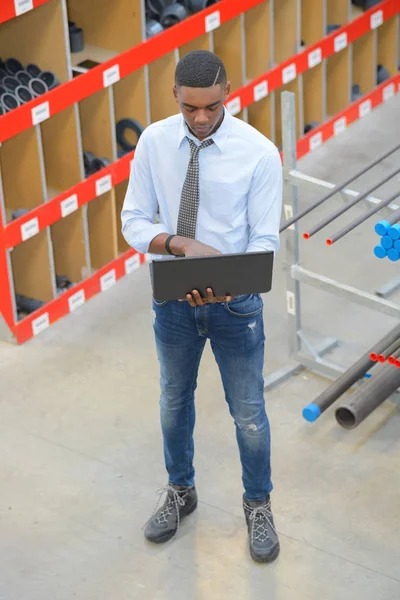 Черный менеджер с ноутбуком на складе — стоковое фото