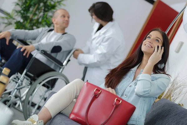 Mulher na sala de espera clínica falando ao telefone sorrindo — Fotografia de Stock