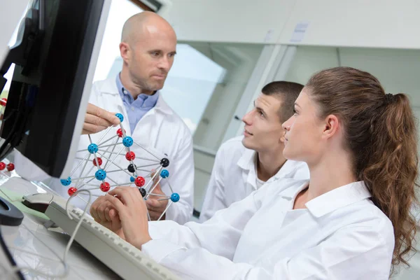 Científico que trabaja con atención con el ordenador portátil y el modelo de ADN en laboratorio — Foto de Stock