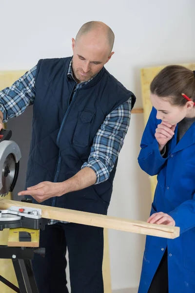 Stážista carpenter sleduje, jak používat kotoučová pila — Stock fotografie