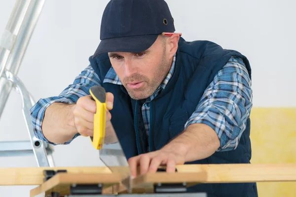 Carpinteiro serrar madeira com serra manual — Fotografia de Stock