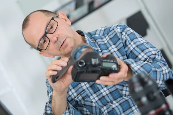 Técnico que examina e repara a câmera dslr — Fotografia de Stock