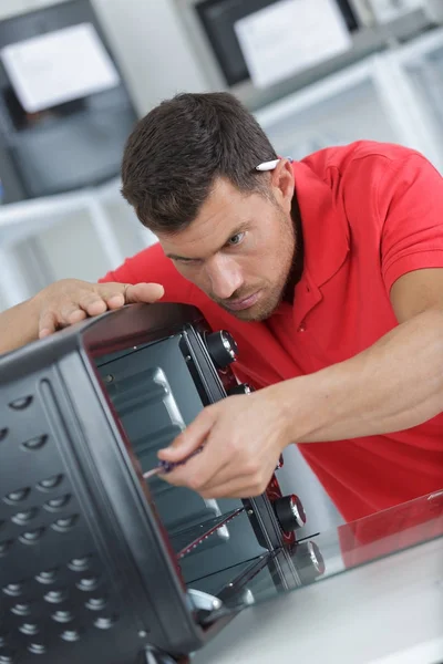 Young male technician repairing oven in kitchen — Stock Photo, Image