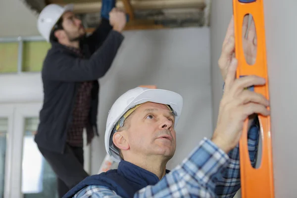 Mature construction worker using level — Stock Photo, Image