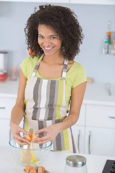 Giovane donna che cucina in cucina rompendo uova — Foto Stock