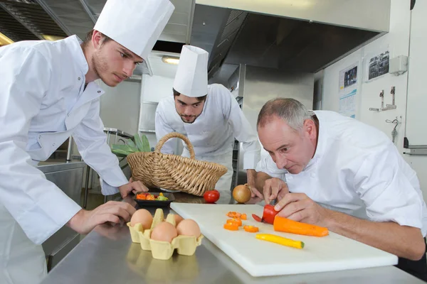 Team von Köchen schneidet Gemüse in der Küche — Stockfoto