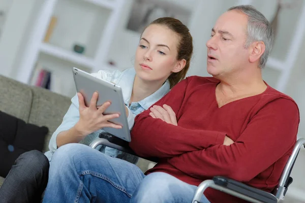 Νεαρή γυναίκα προσπαθεί πατέρα του να χρήση tablet — Φωτογραφία Αρχείου